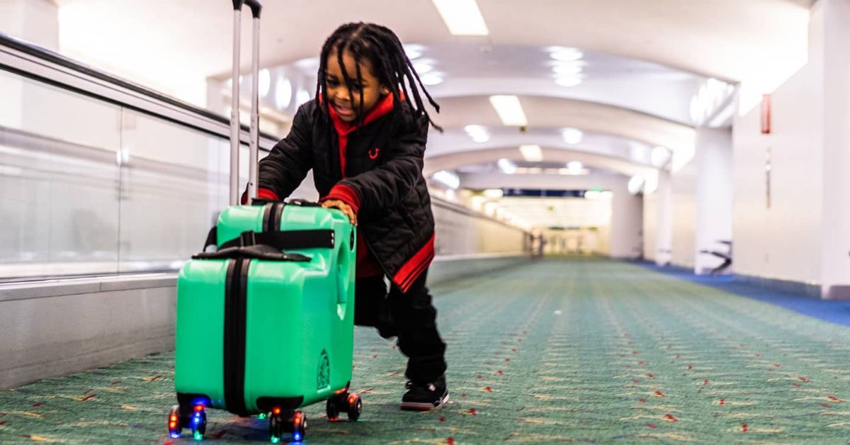 A child carrying a small suitcase through an airport walkway
